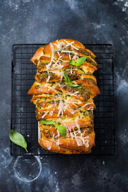 Rozłożony chleb z włoskim pesto z makaronu, bazylią i parmezanem w formie do pieczenia na ciemnym, betonowym tle