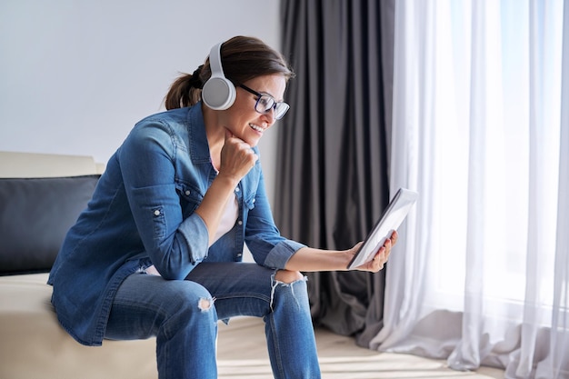 Rozmawiająca kobieta w słuchawkach, patrząca na kamerę internetową cyfrowego tabletu