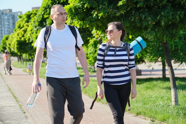 Rozmawiający mężczyzna i kobieta w średnim wieku, para spacerująca wzdłuż ulicy w parku d ludzi