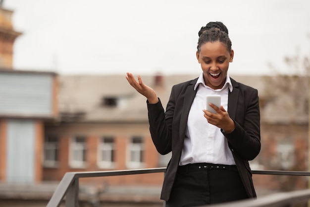 Rozmawiający telefon zdumiony afrykańska bizneswoman w stroju biurowym uśmiechnięta