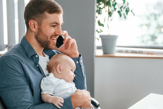 Rozmowa przez telefon Ojciec z maluchem jest w pomieszczeniu w biurze