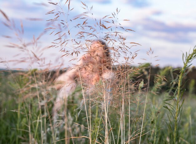 Rozmyta kobieta siedząca na letnim polu z zieloną trawą ciesząca się powolnym życiem w naturze Kobieta w ...