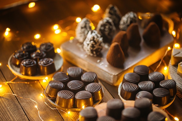 Różne czekoladki na drewnianym stole z girlandą
