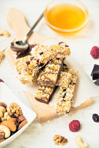 Różne domowe batoniki granola z orzechami, miodem z ciemnej czekolady i jagodami na drewnianej desce