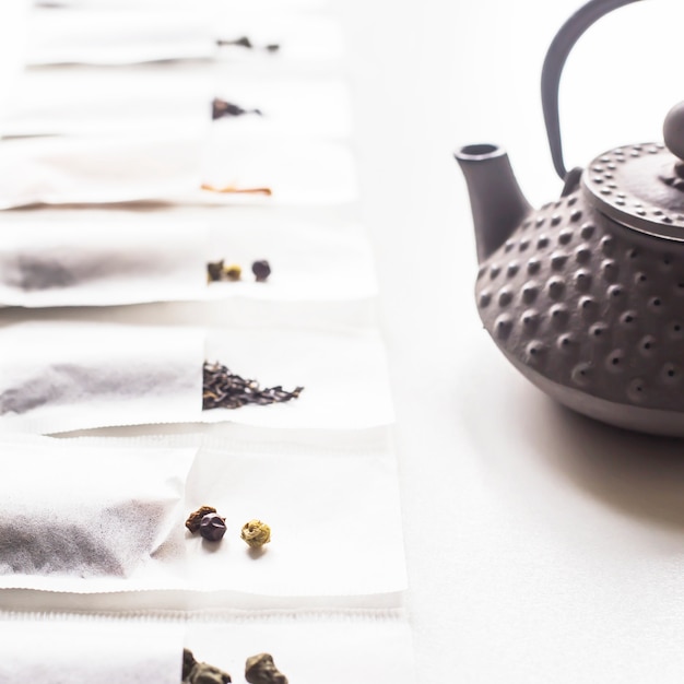 Różne Herbaty W Jednorazowych Workach Filtrowych Do Zaparzania Obok Szarego żeliwa Czajnika Na Białym Tle