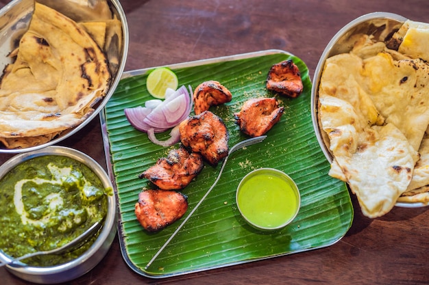 Różne indyjskie jedzenie na ciemnym tle drewnianych. Dania i przekąski kuchni indyjskiej. Curry, kurczak maślany, ryż, soczewica, paneer, samosa, naan, chutney, przyprawy. Miski i talerze z indyjskim jedzeniem.