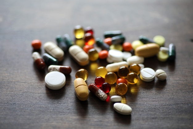 Różne kolorowe leki i tabletki na drewnianym stole z teksturą