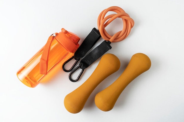 Zdjęcie różne kolorowe urządzenia do ćwiczeń fitness i sportowych pomarańczowe hantle i ekspandery piłki i opaski fitness leżące na białym tle
