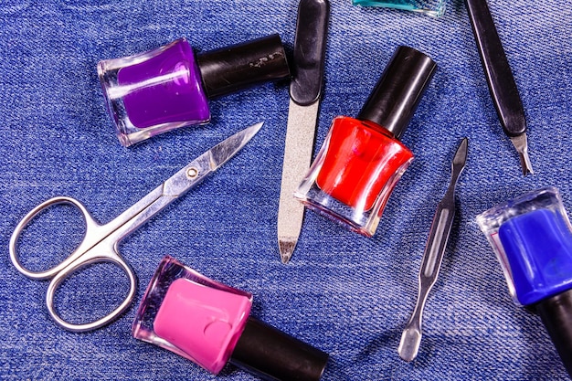 Różne narzędzia do manicure i lakiery do paznokci na niebieskich dżinsach Widok z góry