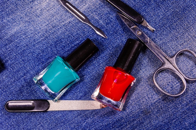 Różne narzędzia do manicure i lakiery do paznokci na niebieskich dżinsach Widok z góry