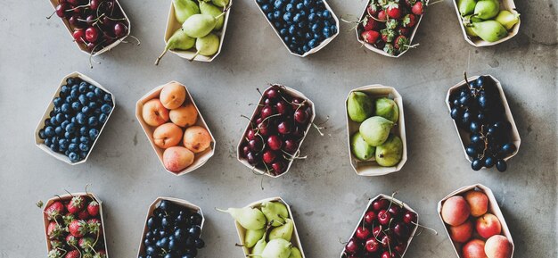 Różne owoce i jagody na szarym betonowym tle, szeroka kompozycja