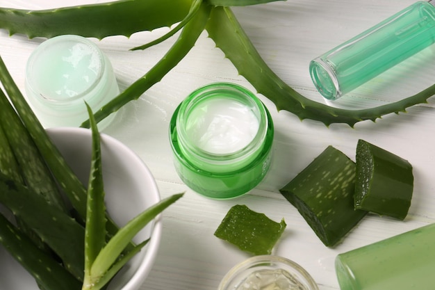Różne produkty kosmetyczne i cięte liście aloe vera na białym drewnianym stole powyżej