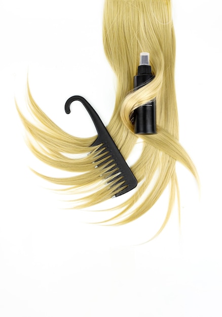 Różne profesjonalne narzędzia fryzjerskie czarna szczotka do włosów z lakierem do włosów i pasmem blond włosów na białym tle leżał płasko Koncepcja spa do pielęgnacji włosów
