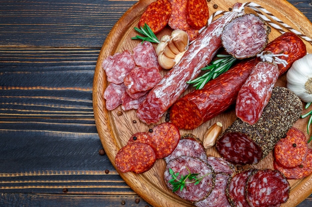 Różne rodzaje suszonej organicznej kiełbasy salami na drewnianej desce do krojenia