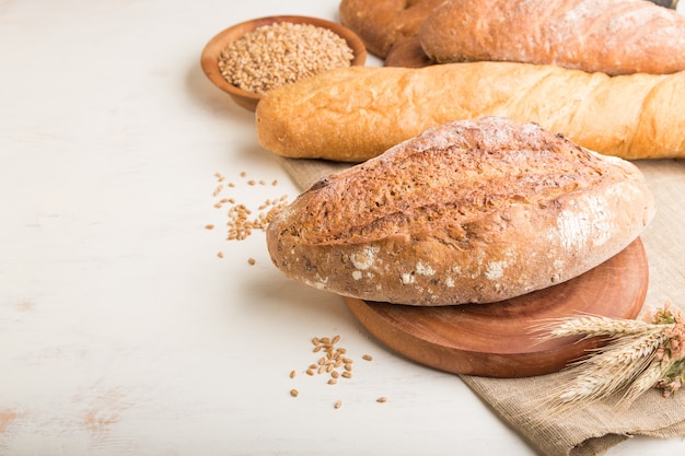 Różne rodzaje świeżego pieczywa na białej powierzchni drewnianych. widok z boku, kopia przestrzeń.