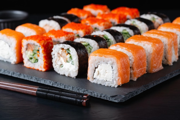 Różne rolki sushi na czarnym tle