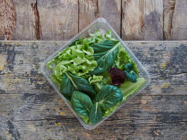 Różne sałaty i liście warzyw na sałatce do zabrania na kwadratowym plastikowym opakowaniu