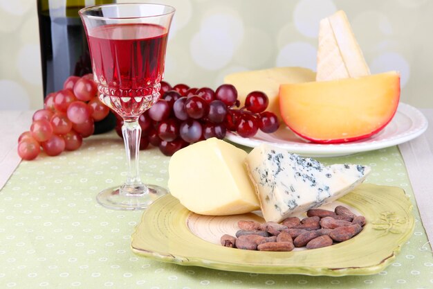 Różne sery winogronowe i kieliszki do wina na stole na jasnym tle