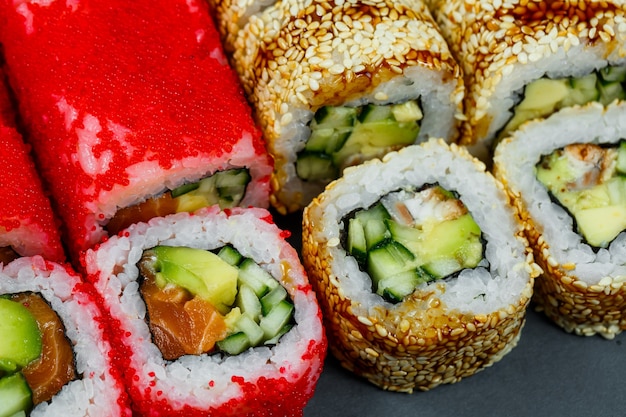 Zdjęcie różne sushi. sushi roll z awokado, ogórkiem. roll sushi z łososiem i kawiorem. roll sushi z tuńczykiem i kawiorem. na jasnym tle. japońskie jedzenie. widok z góry