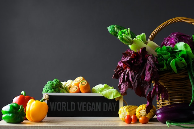 Różne świeże kolorowe warzywa z tablicą z napisami mówią o światowym dniu wegan na drewnianym stole