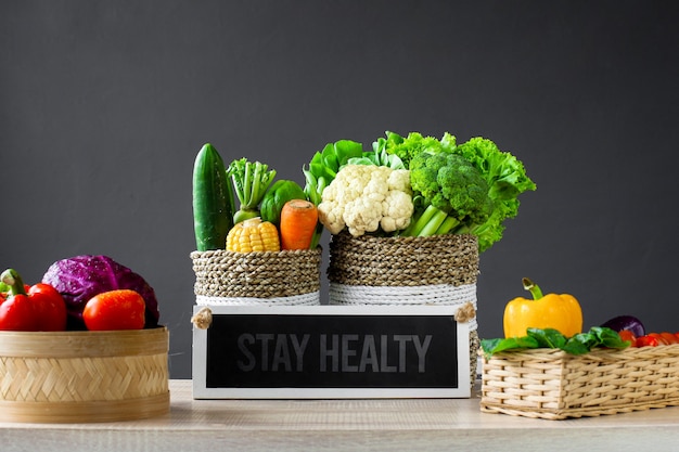 Różne świeże kolorowe warzywa z tablicą z napisami mówią, że pozostań zdrowy na drewnianym stole