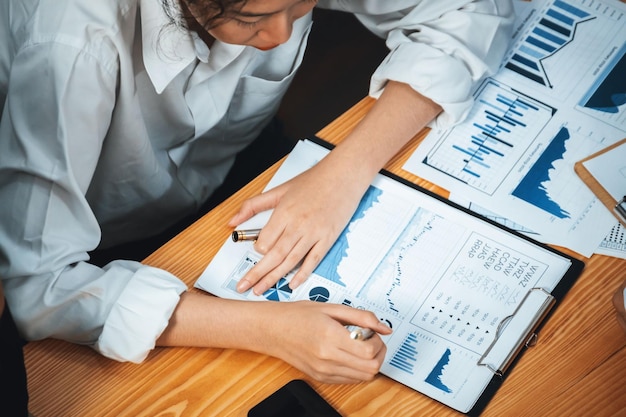 Różnorodna grupa analityków biznesowych analizuje dane finansowe, raporty papierowe na biurowym stole, wykresy i wykresy na desce rozdzielczej według analizy biznesowej dla strategicznego planowania marketingowego.