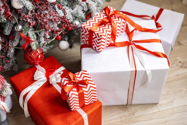 Różnorodne kolorowe prezenty świąteczne stoją w pobliżu ozdobnej choinki w domu na