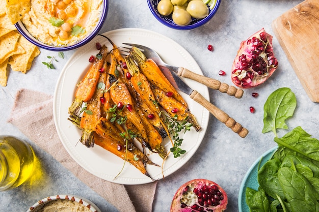 Różnorodne zdrowe wegańskie przekąski, wyśmienite dipy. Hummus, pieczona marchewka, ryż z tempeh w ceramicznych misach oglądanych z góry, żywność na bazie roślin