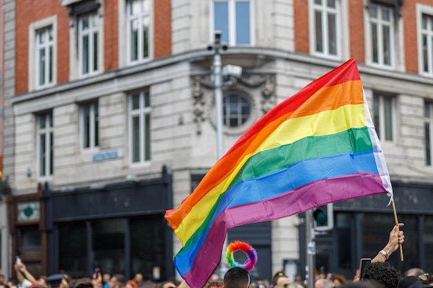 Różnorodni ludzie spacerują na paradzie gejów ulicami miasta z flagami