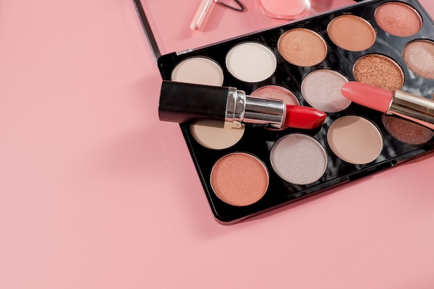 Różnorodni makeup produkty na różowym tle z copyspace