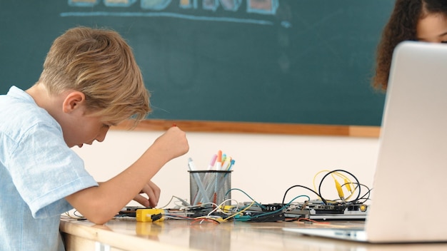 Różnorodni studenci pracują razem nad naprawą głównej tablicy w pedagogii klasy.