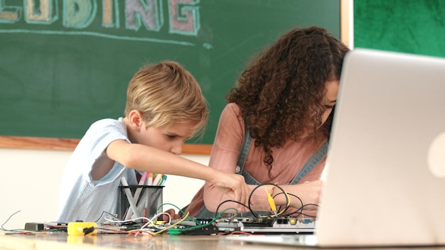 Różnorodni uczniowie pracują razem nad naprawą głównej deski w klasie pedagogicznej