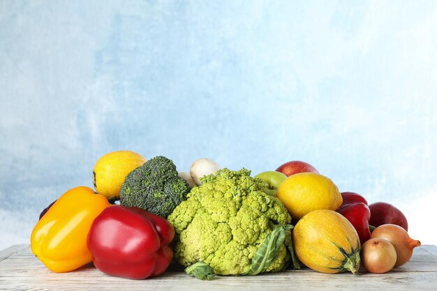 Różnorodność świeżych pysznych warzyw i owoców na stole na kolorowym tle