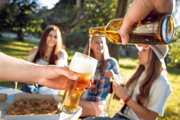 Rozochoceni przyjaciele na pinkinie w parku. Jedzenie pizzy