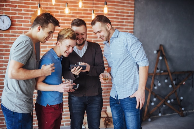 Rozochoceni Starzy Przyjaciele Komunikują Się Ze Sobą I Oglądają Telefon, Kieliszki Whisky W Pubie. Rozrywka Styl życia. Wi-fi Połączonych Ludzi Na Spotkaniu Przy Stole Barowym