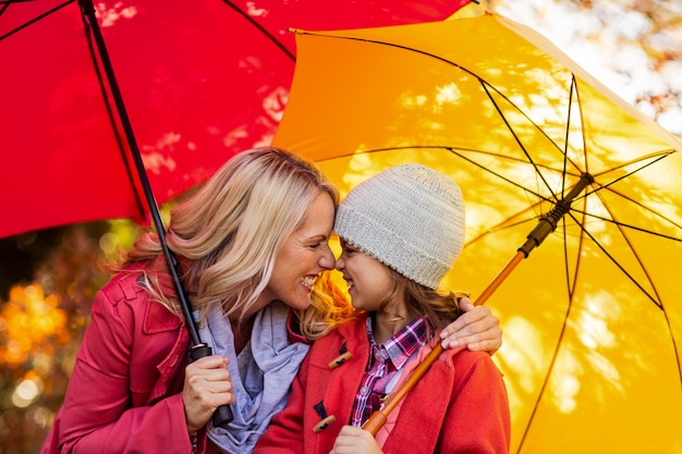 Rozochocona matka i córka z parasolem przy parkiem