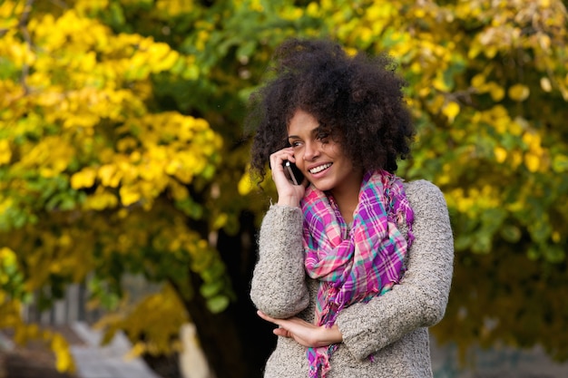 Rozochocona młoda kobieta opowiada na telefonie komórkowym outside