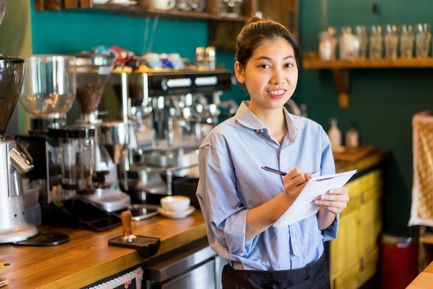 Rozochocona ufna Azjatycka kelnerka robi notatkom w papierze.