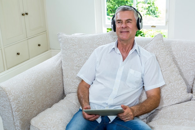 Rozochoconego starszego mężczyzna słuchająca muzyka w domu