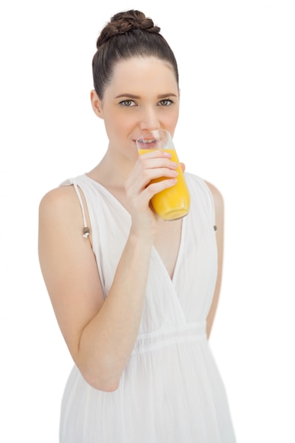 Zdjęcie rozochocony model w biel sukni pije sok pomarańczowego