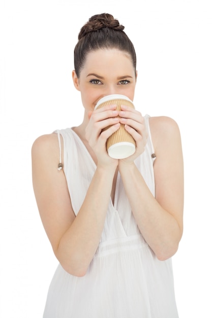 Rozochocony naturalny model w biel sukni pije kawę