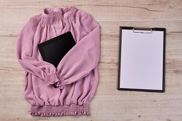 Różowa bluzka z długim rękawem z tabletem i schowkiem na białym tle na biurko