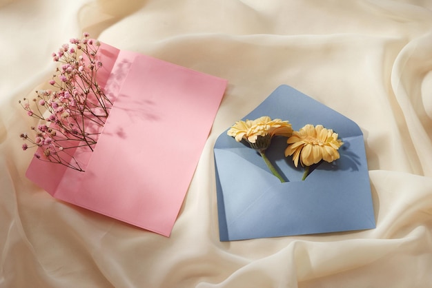Różowa i niebieska koperta z wiosenną kompozycją kwiatową Płaski widok z góry
