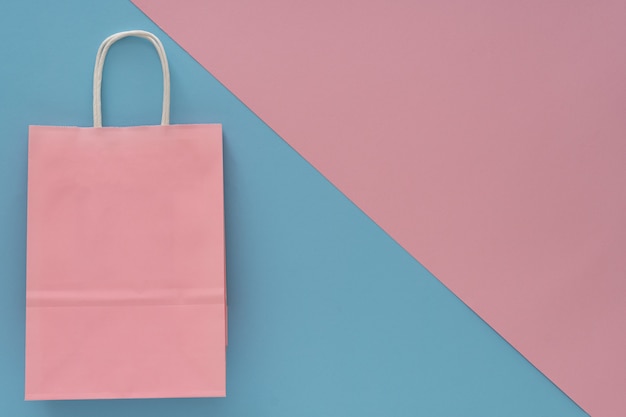 Zdjęcie różowa papierowa torba na zakupy na różowym i niebieskim tle. widok z góry... miejsce na tekst,