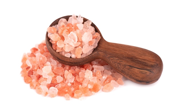 Różowa sól himalajska w drewnianą łyżką, na białym tle. Różowa sól himalajska w kryształkach.
