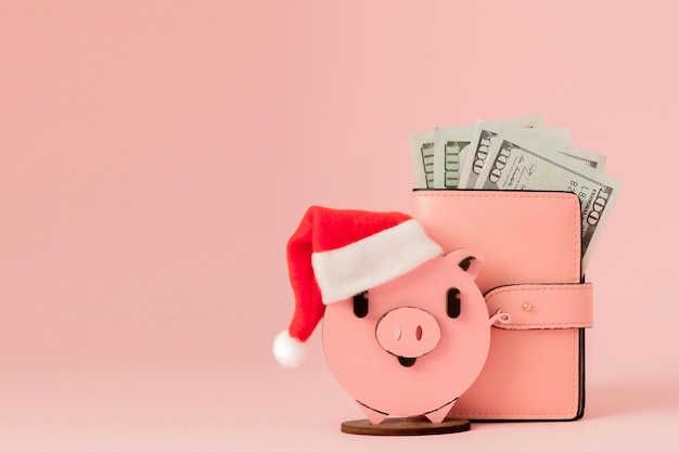 Różowa świąteczna świnia i torebka z dolarami na różowym tle