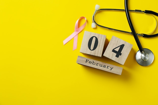 Różowa wstążka świadomości, stetoskop i 4 lutego na żółtym tle