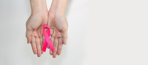 Różowa wstążka w dłoni kobiety dla kampanii raka piersi, aby zachęcić i opiekować się pacjentką.