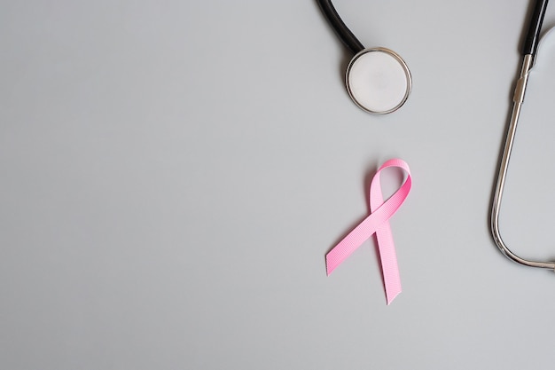 Różowa wstążka ze stetoskopem na szarym tle, świadomość raka piersi