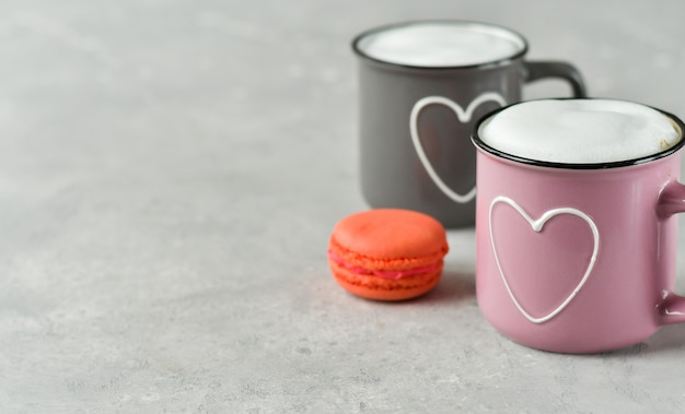 Różowe i szare filiżanki z cappuccino i macaron